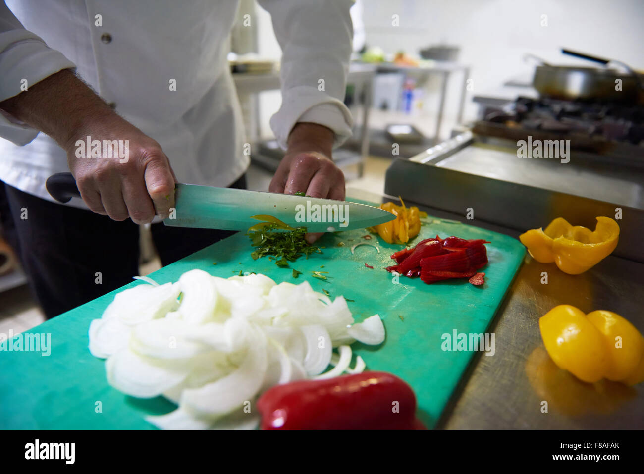 chef in hotel kitchen slice vegetables with knife and prepare food ...