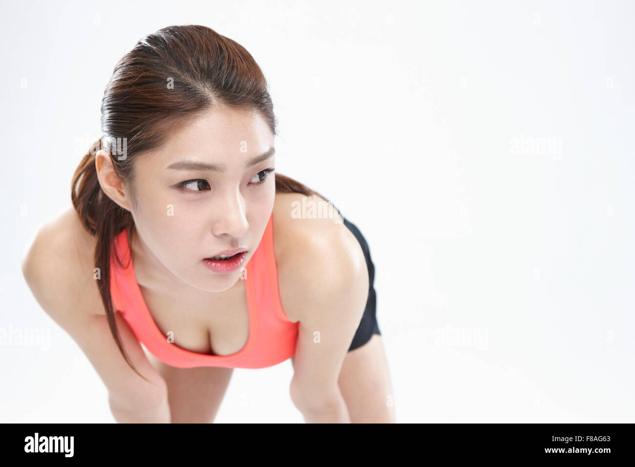 Woman in sportswear bending her upper body down and looking aside Stock Photo