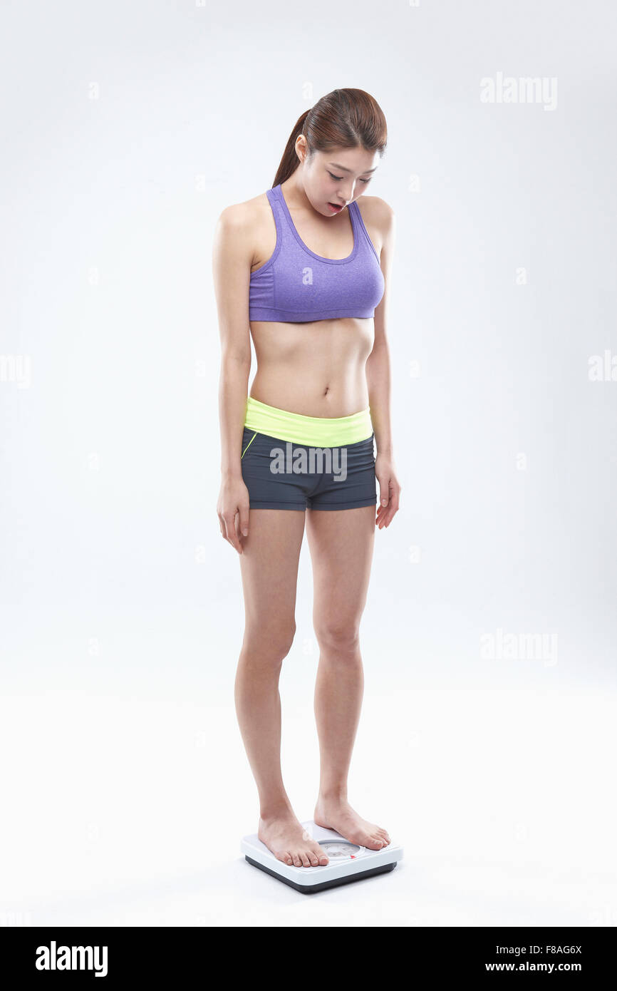 Woman in sportswear standing on a scale and looking down Stock Photo