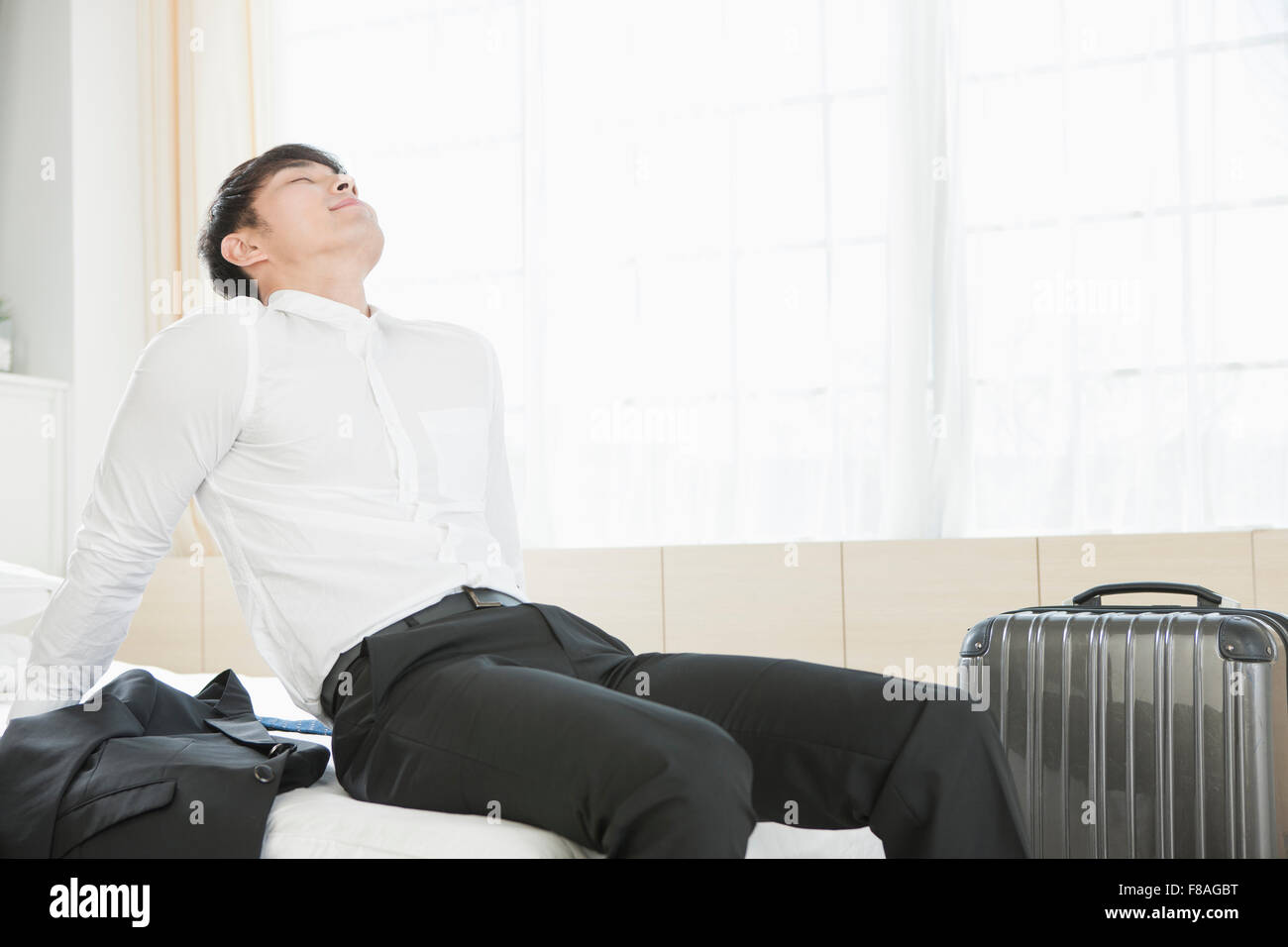 Man in formal outfits leaning back on bed Stock Photo Alamy
