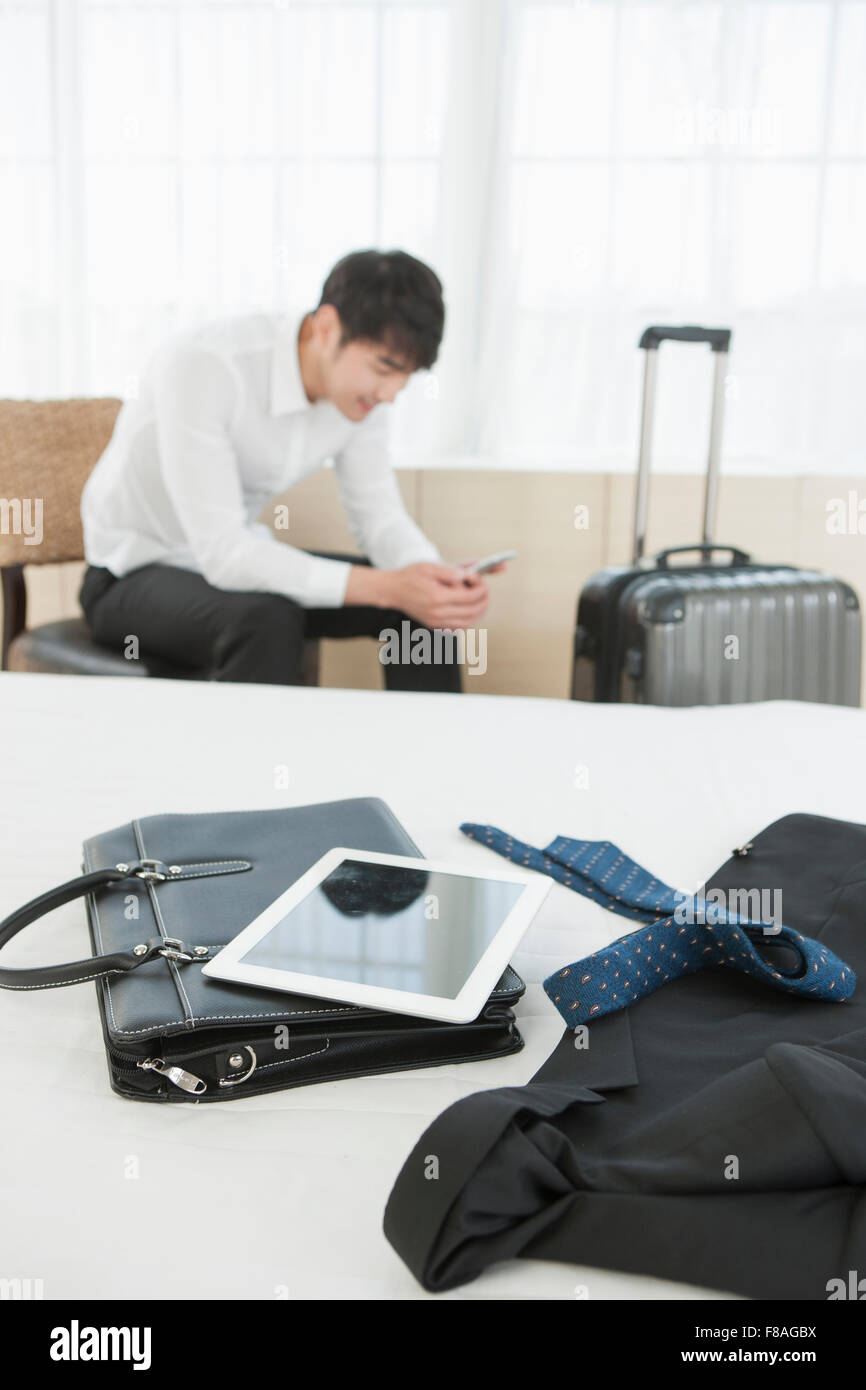 Business trip related objects on bed with the back ground of a man seated on a chair Stock Photo