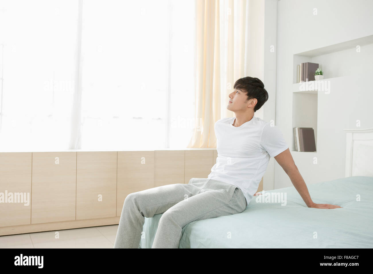 Man leaning his back on the bed and staring upward Stock Photo Alamy