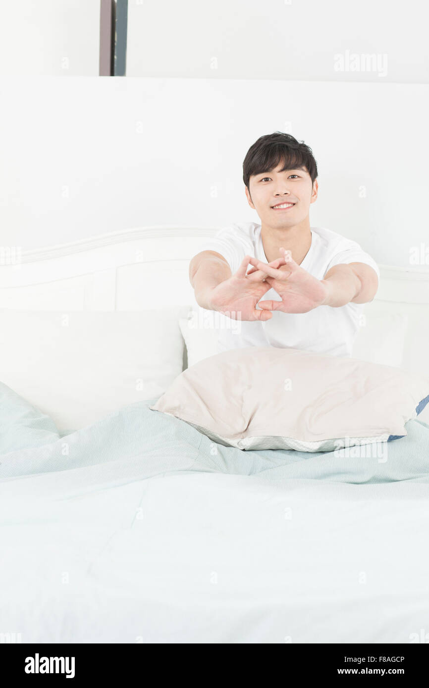 Man stretching his arms in bed Stock Photo