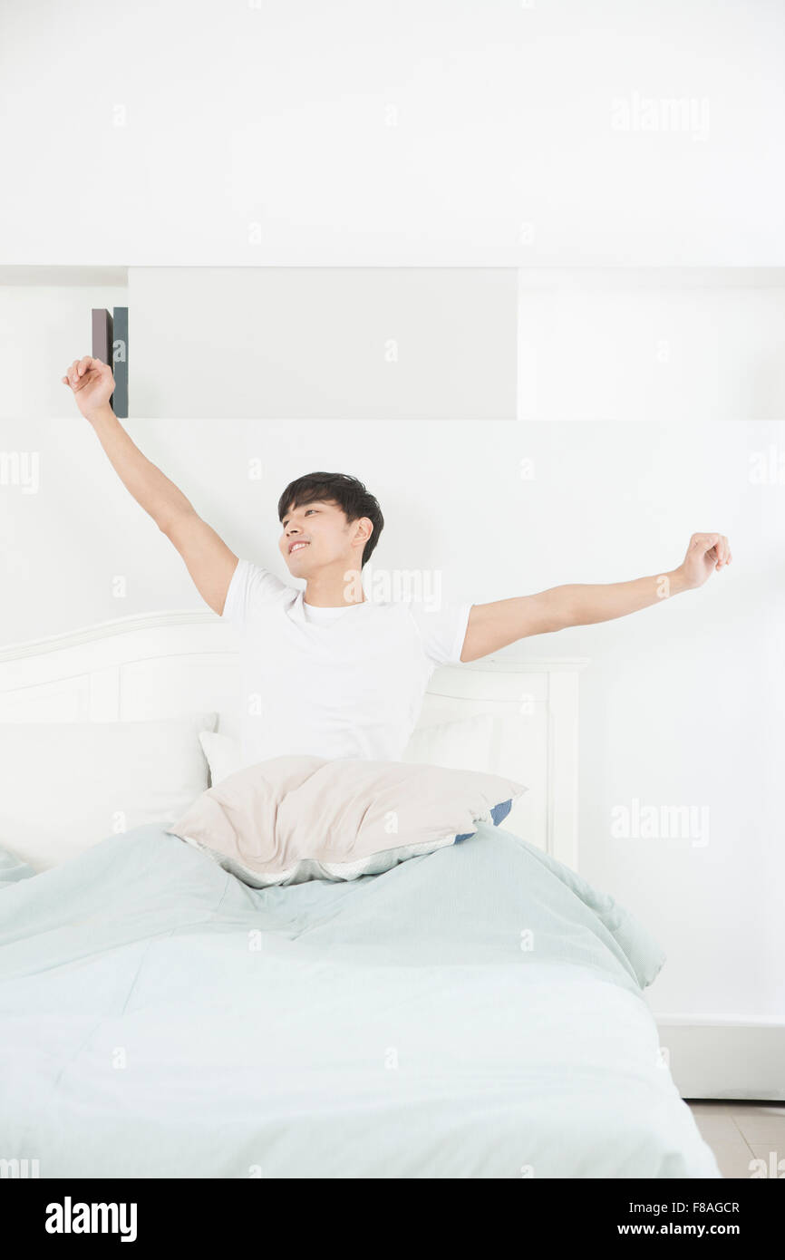 Man stretching his arms in bed with arms open Stock Photo