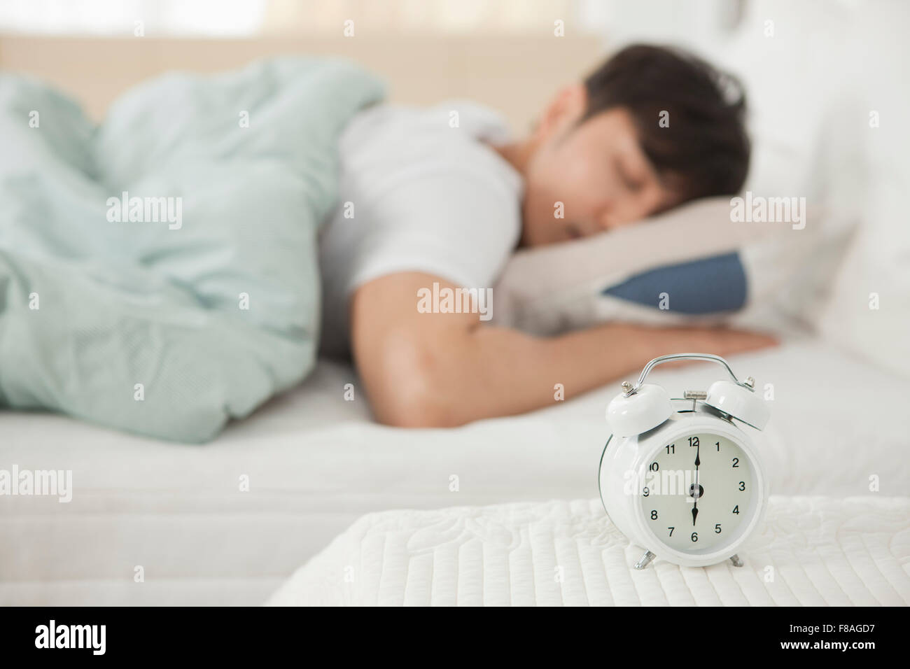 Alarm clock with the background of a sleeping man Stock Photo