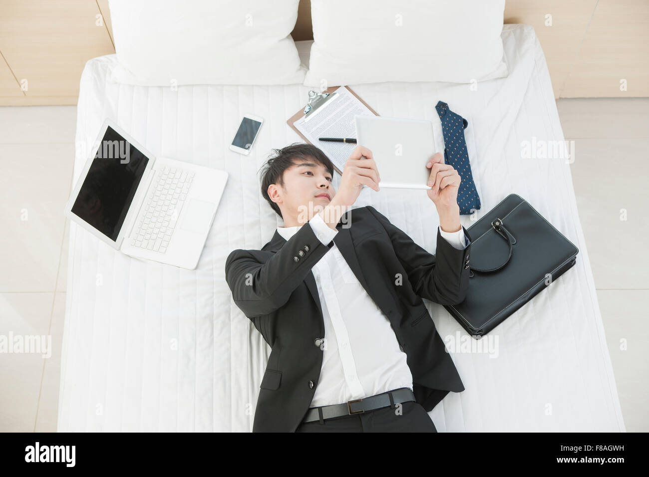 High angle of a man lying down in bed and looking at the tablet PC Stock Photo