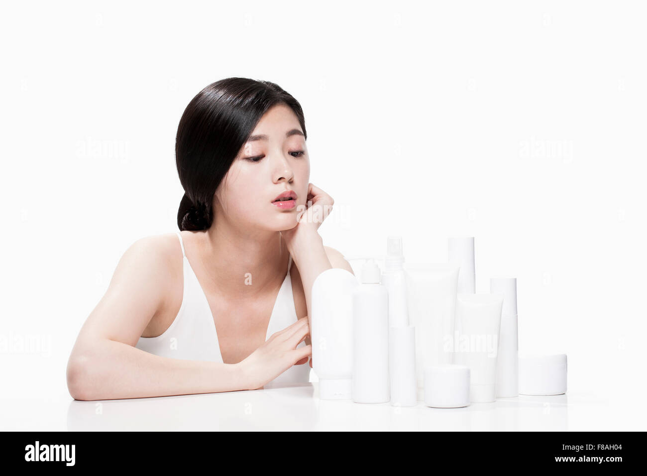 Woman seated at the table with her hand under her chin and staring at various products on the table Stock Photo