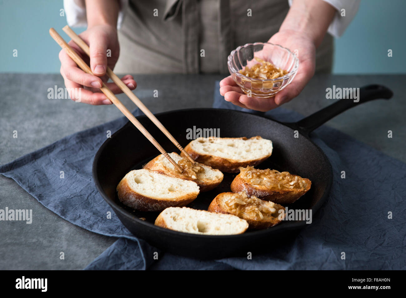 Garnish being placed on the slices of baguette in the pan Stock Photo