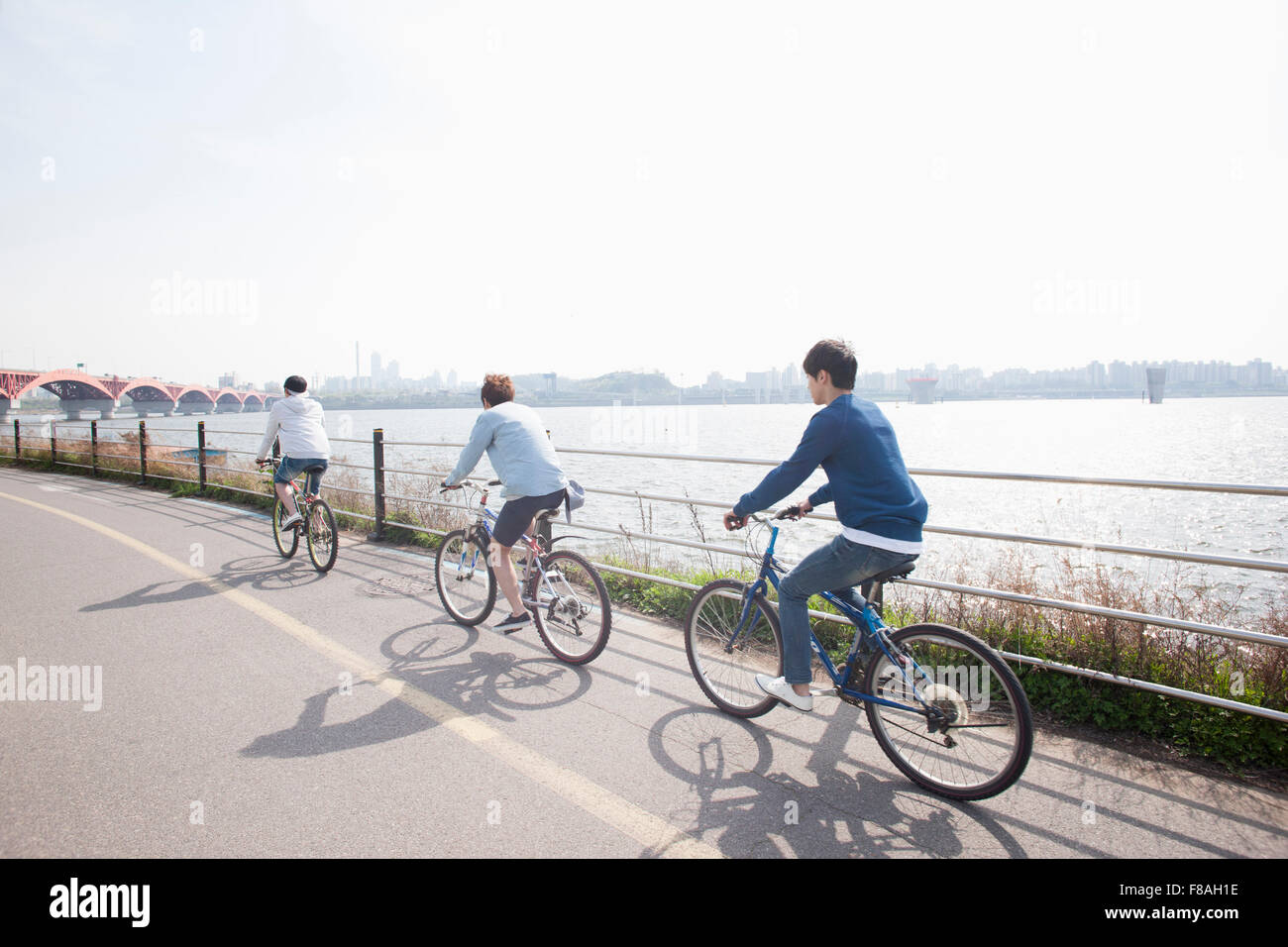 Three young men riding a bike in a row Stock Photo