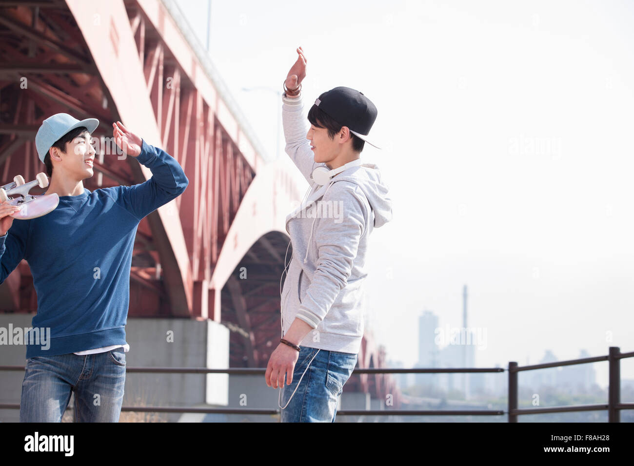 Two men wearing a cap and giving high-fives to each other Stock Photo