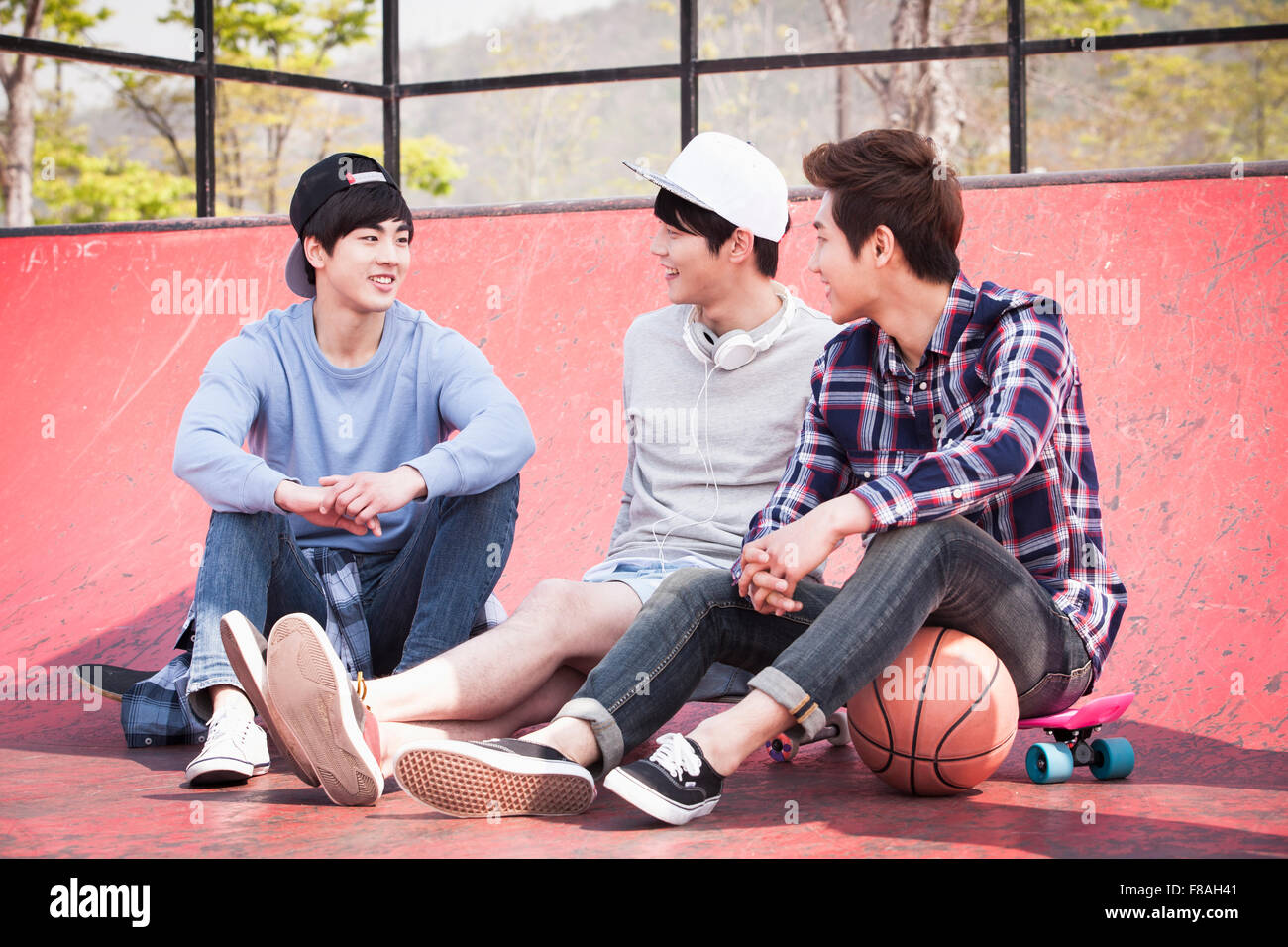 Three men sitting down on the skateboard court Stock Photo