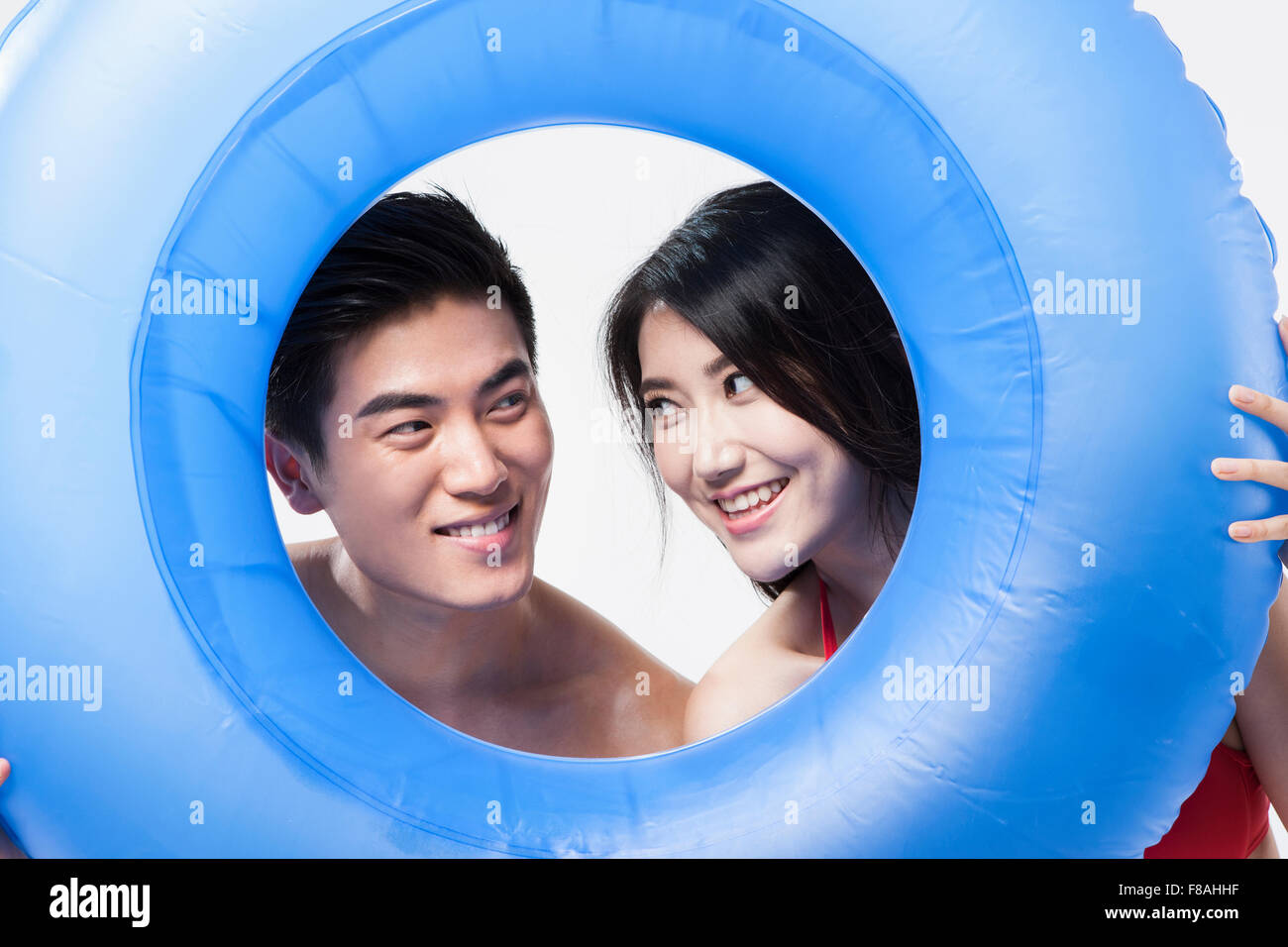 Couple looking through the hole of inner tube and staring each other Stock Photo
