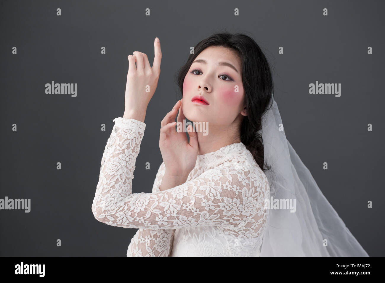 Asian woman in white lace dress and lace veil with pink blush make