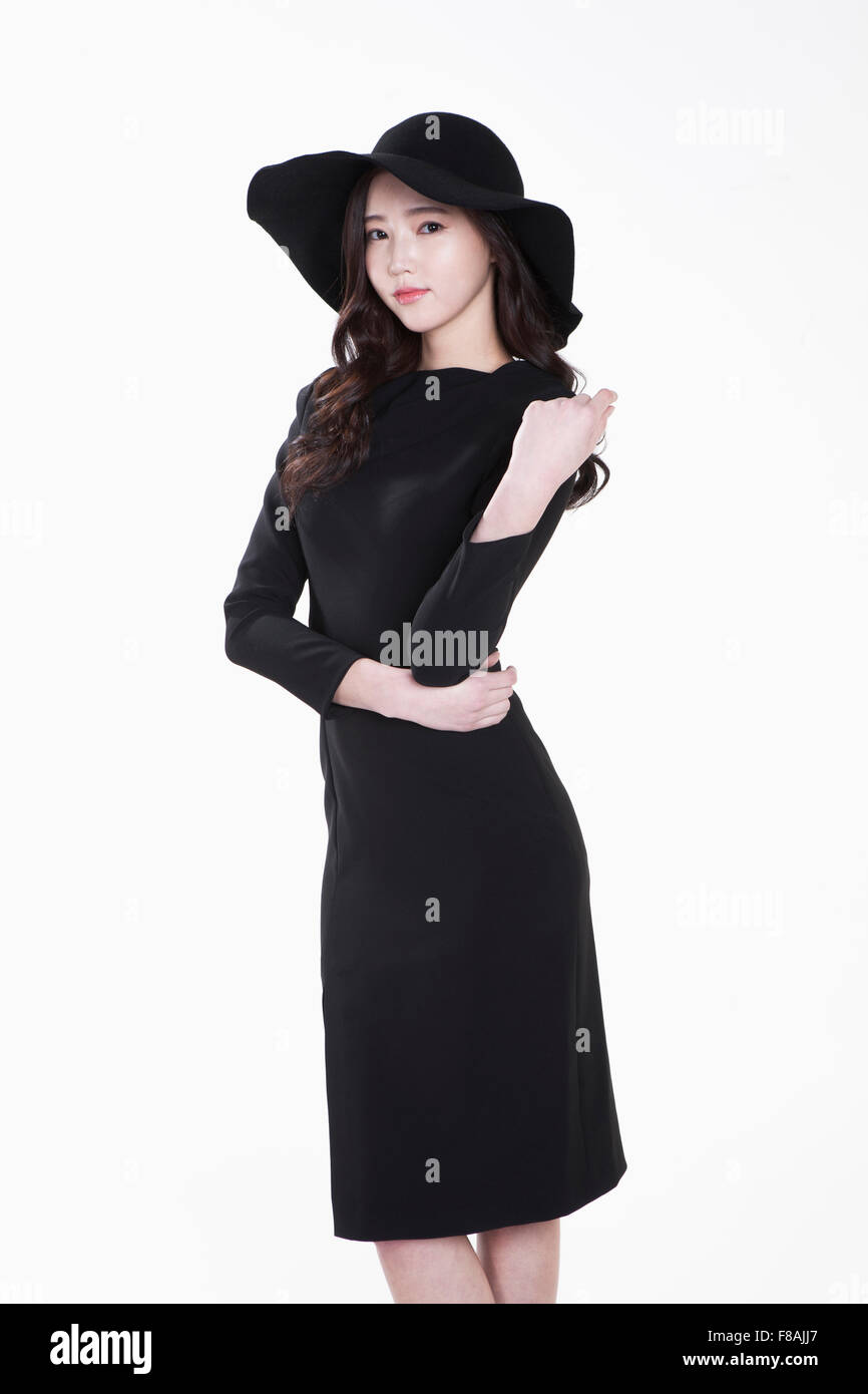 Young woman in black hat and black dress making a pose with her hand on ...