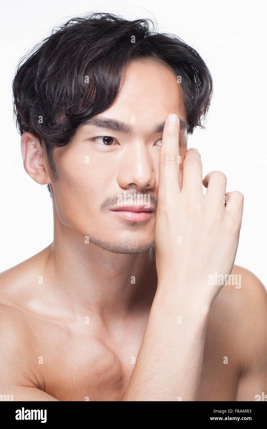 Portrait of young Asian man covering one of his eyes with finger Stock Photo