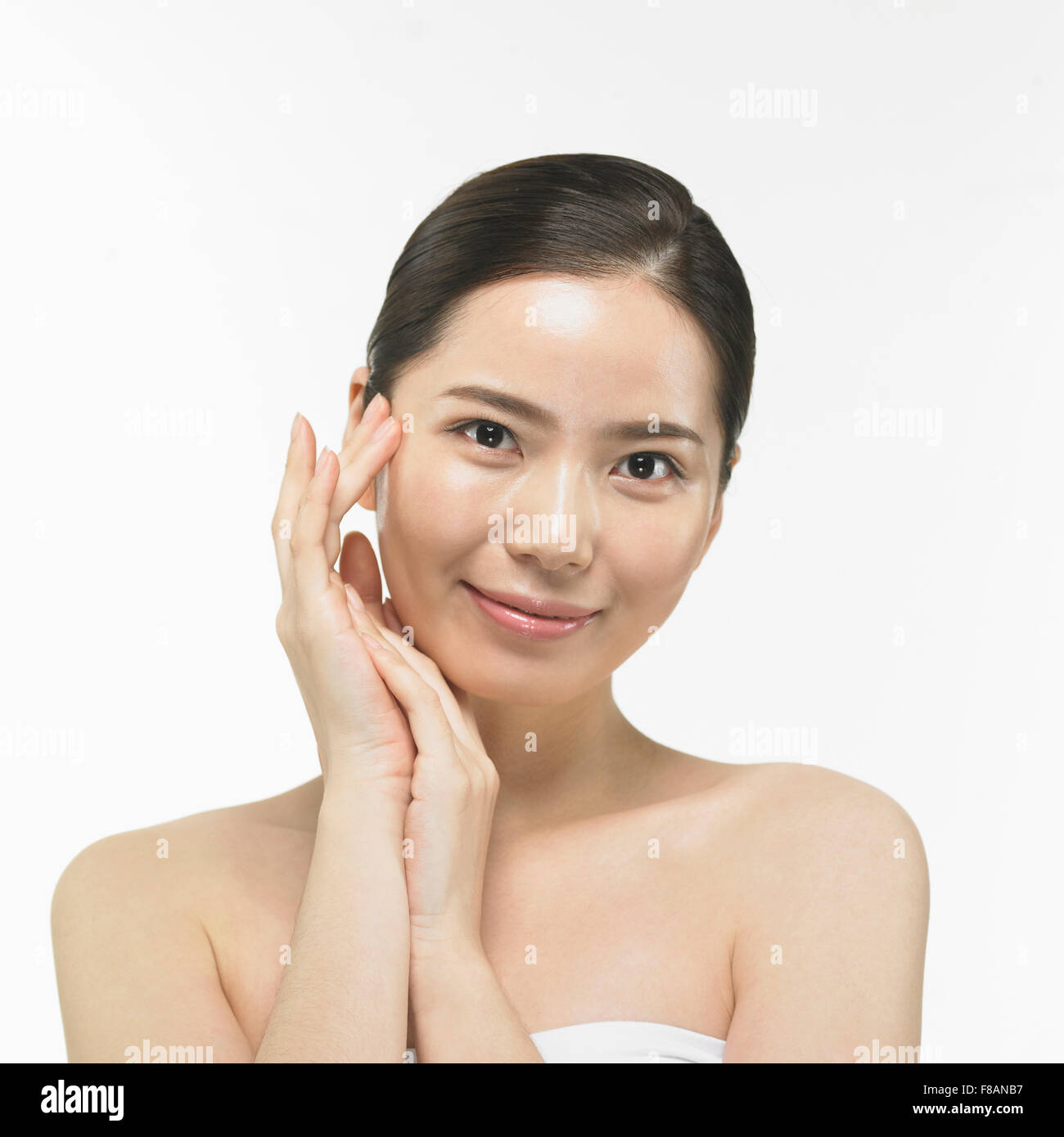 Portrait of smiling Korean woman staring at front touching her face Stock Photo