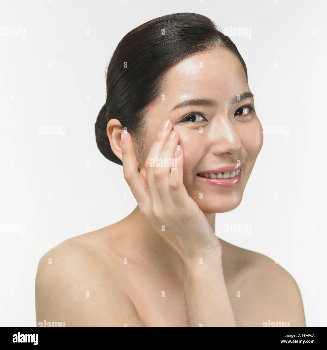 Portrait of Korean woman touching her face with a hand staring at front with a big smile Stock Photo