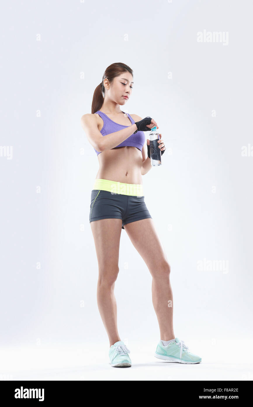 Confident slim woman standing uncapping waterbottle looking down Stock Photo
