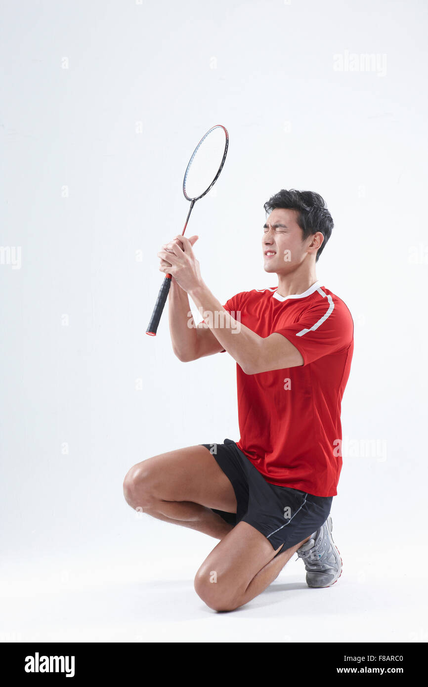 Man sitting down with folded hands and closed eyes holding a badminton racket Stock Photo