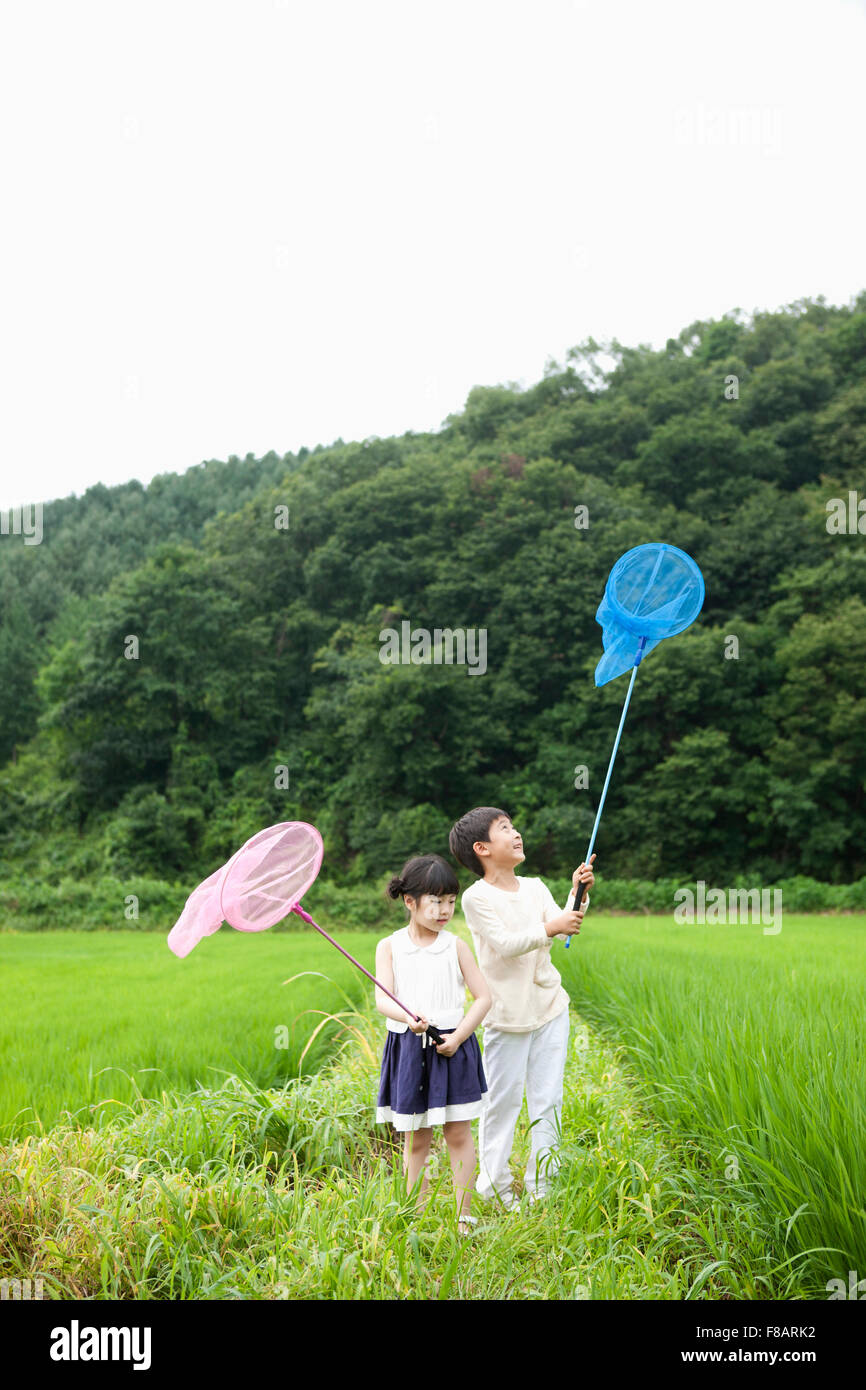 Boy and girl standing with nets on lane through rice fields in spring Stock Photo Alamy