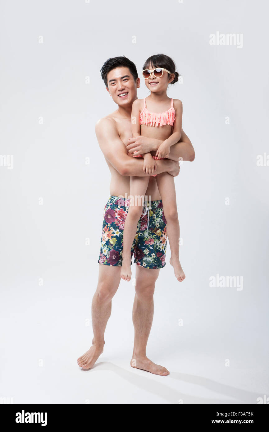 Father and girl in swimsuits staring at front with smiles Stock Photo