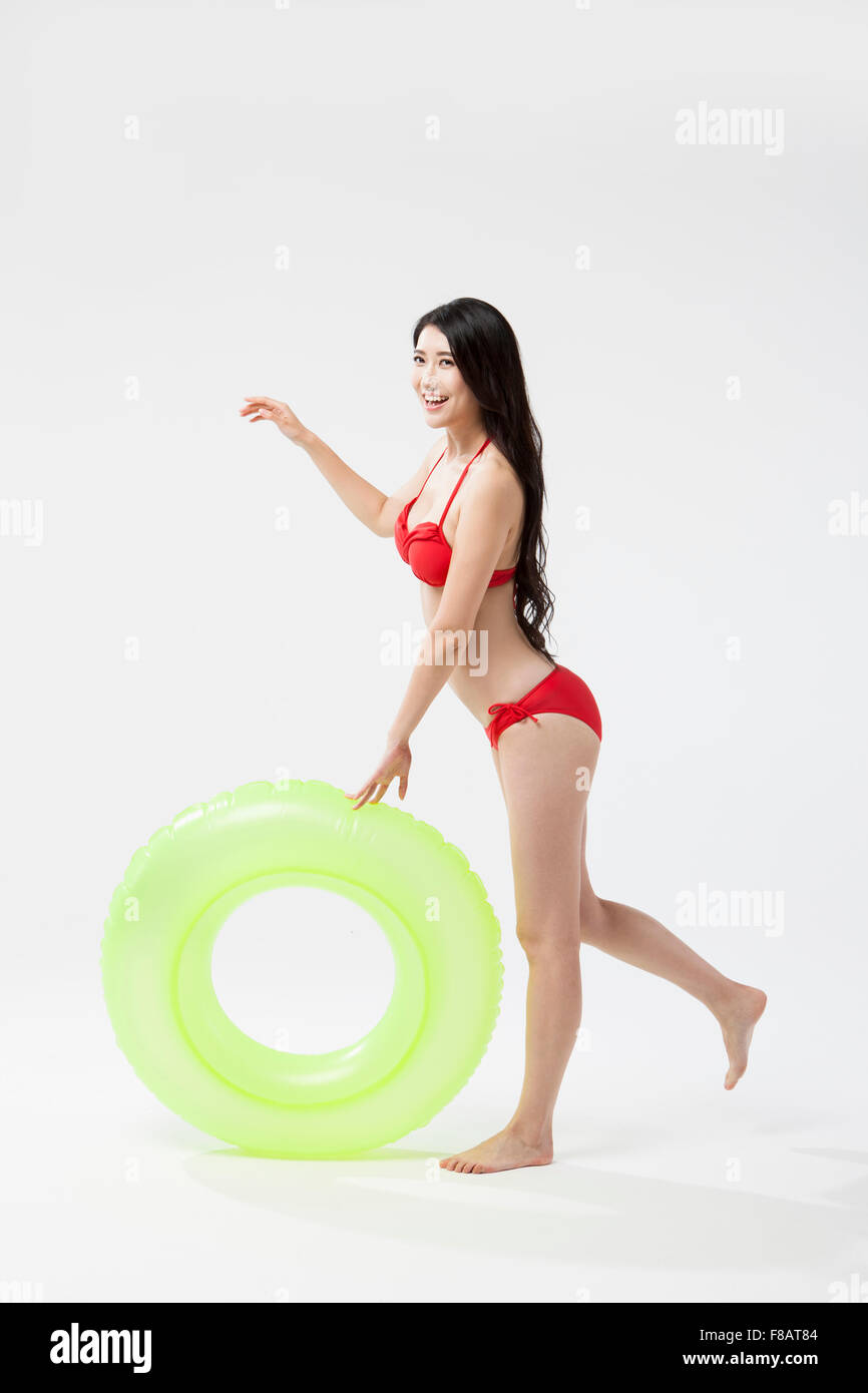 Smiling woman in bikini standing on one foot with a tube Stock Photo