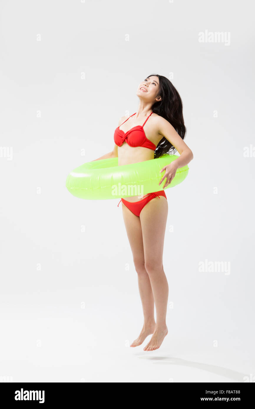 Woman in bikini jumping with a tube looking up raising head Stock Photo