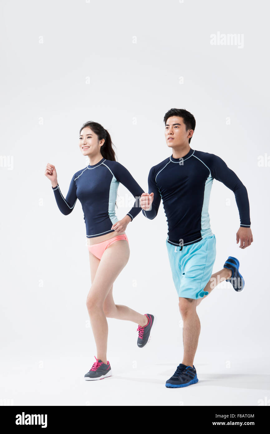 Couple in swimsuits running looking up with smiles Stock Photo