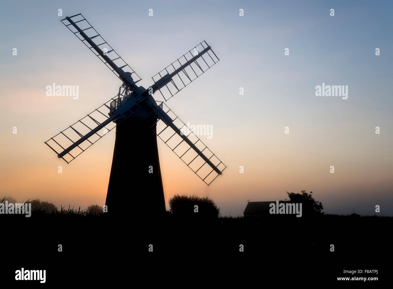 Windmill in stunning landscape on beautiful Summer sunrise Stock Photo