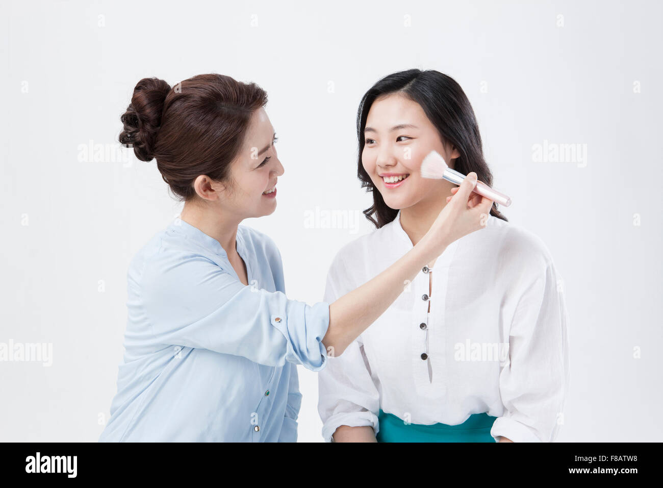 Portrait of mother and daughter applying make up with a brush Stock Photo