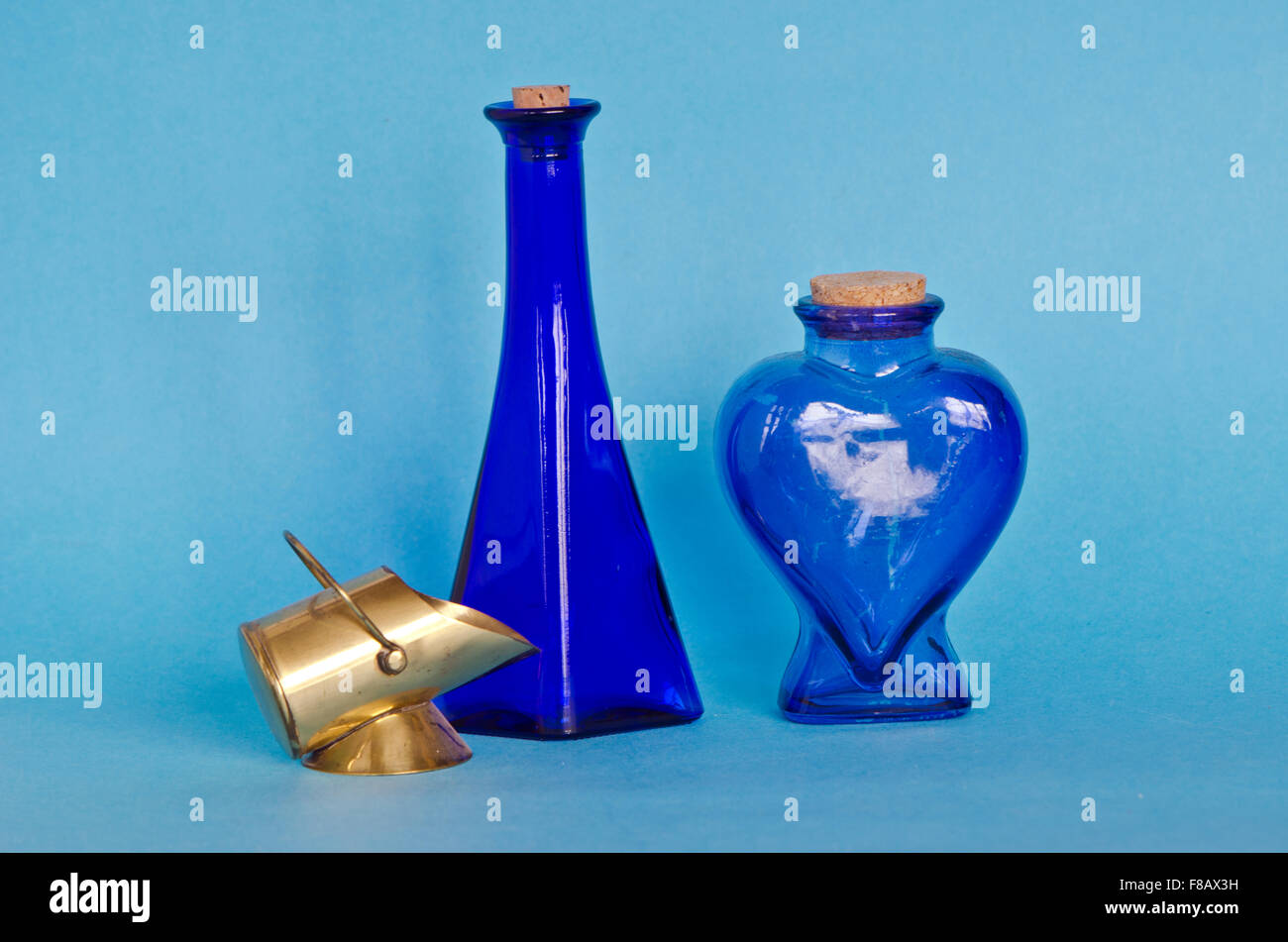 Two decorative blue glass bottles with decorative brass object on blue