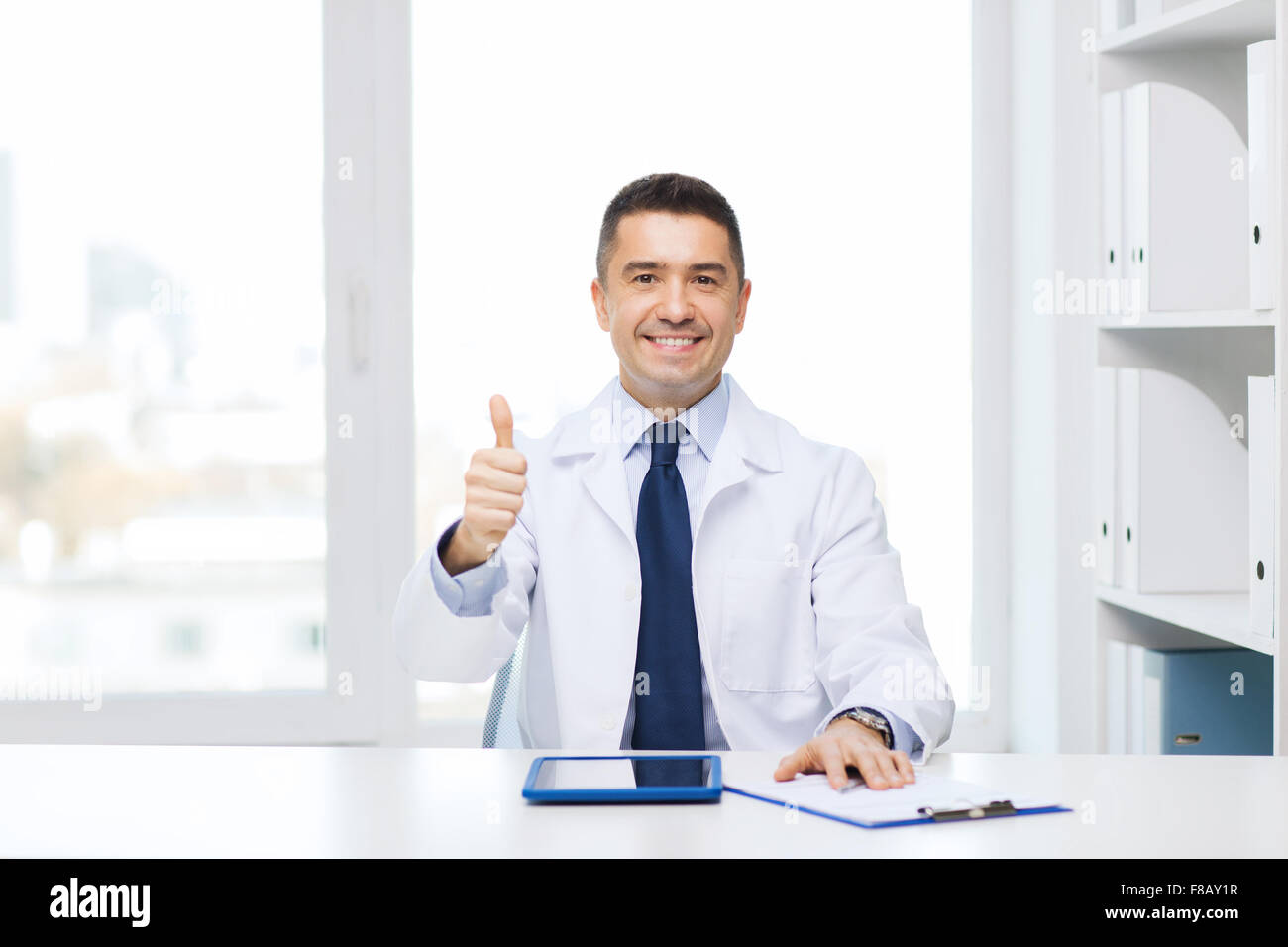 smiling doctor with tablet pc showing thumbs up Stock Photo - Alamy