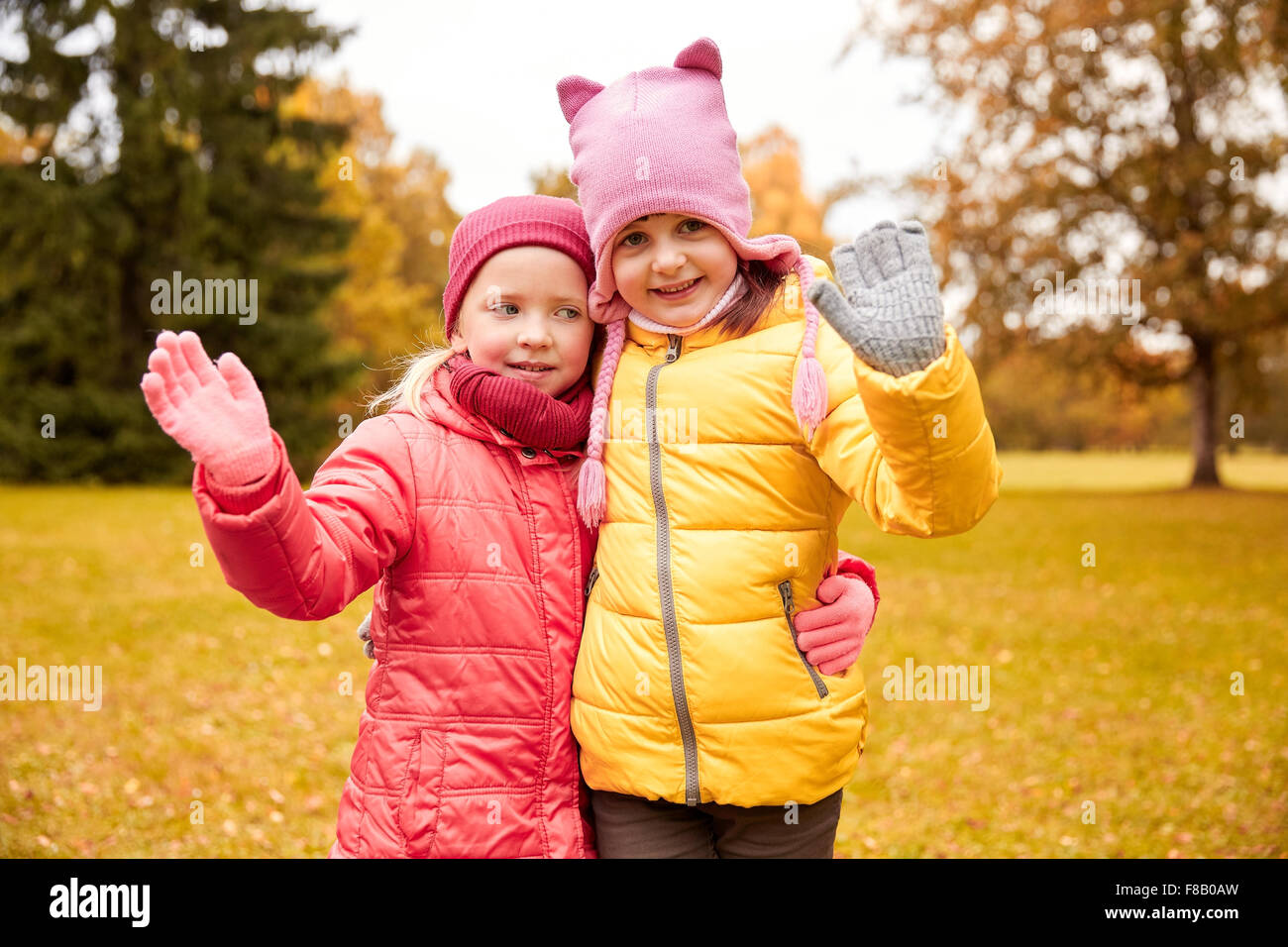 two happy little girls waving hand in autumn park Stock Photo - Alamy