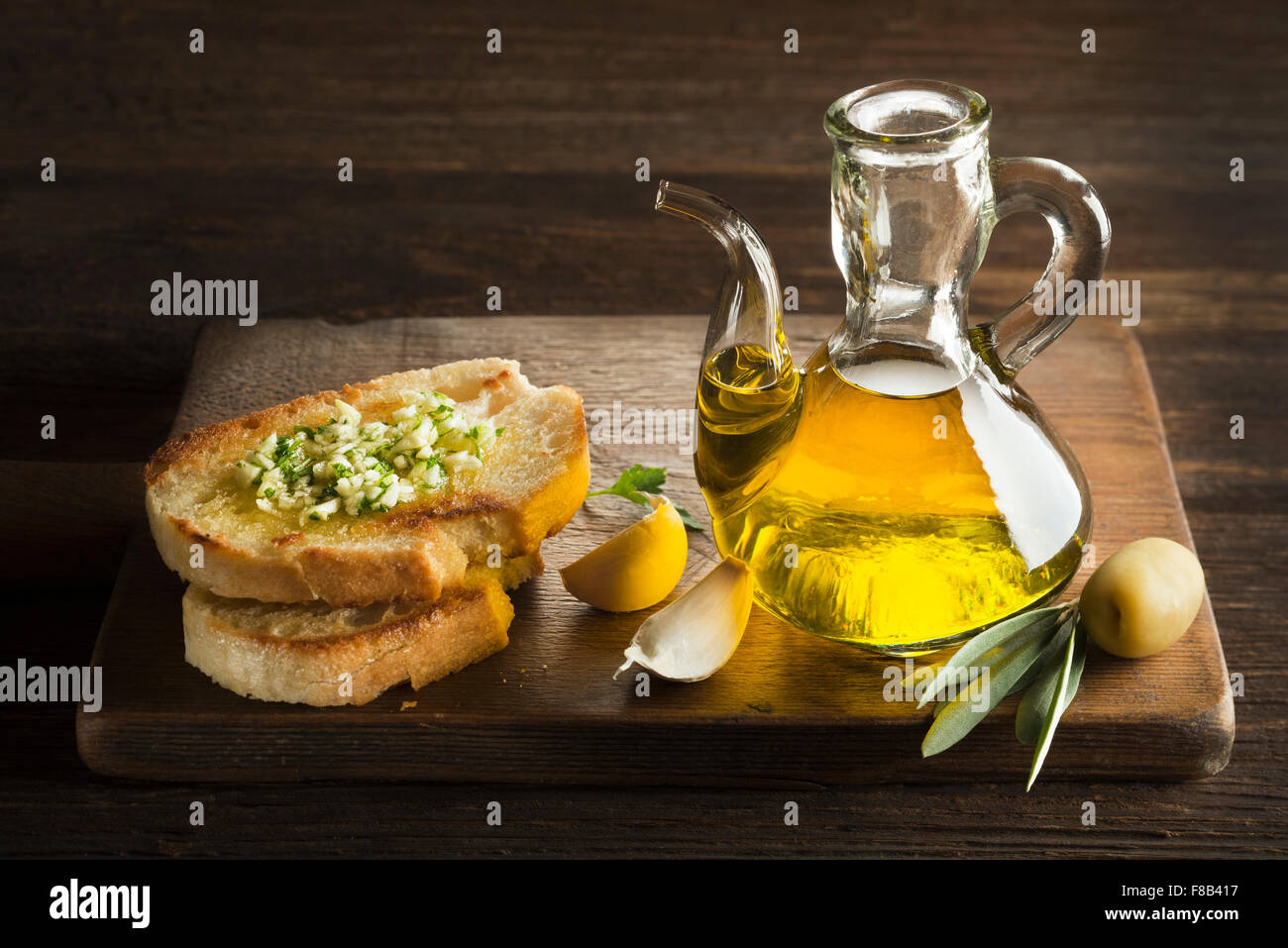 Toasted bread with garlic, herbs and olive oil on wooden background