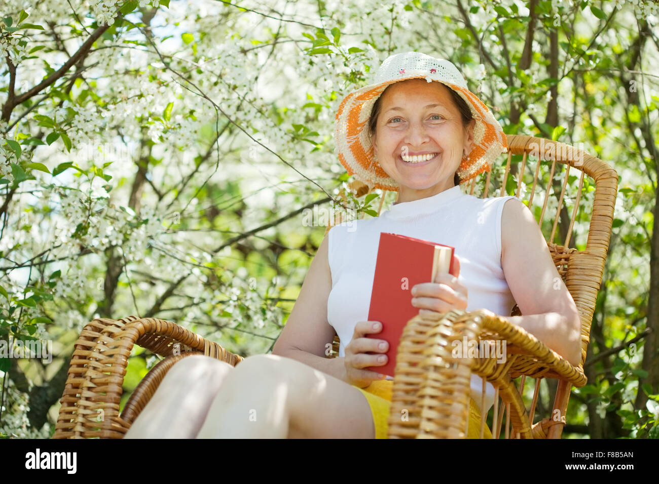 Happy mature woman in rocking-chair against bloom garden Stock Photo ...