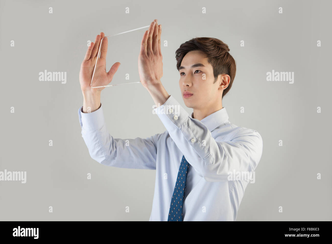 Businessman holding touch screen up high close to his face Stock Photo