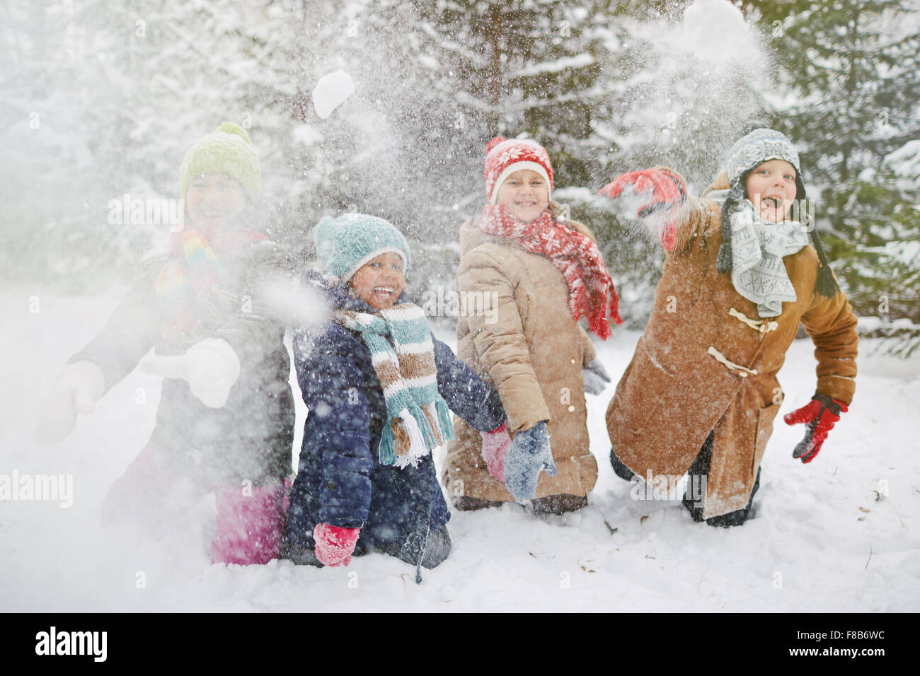 Happy children in winter-wear playing snowballs in park Stock Photo - Alamy