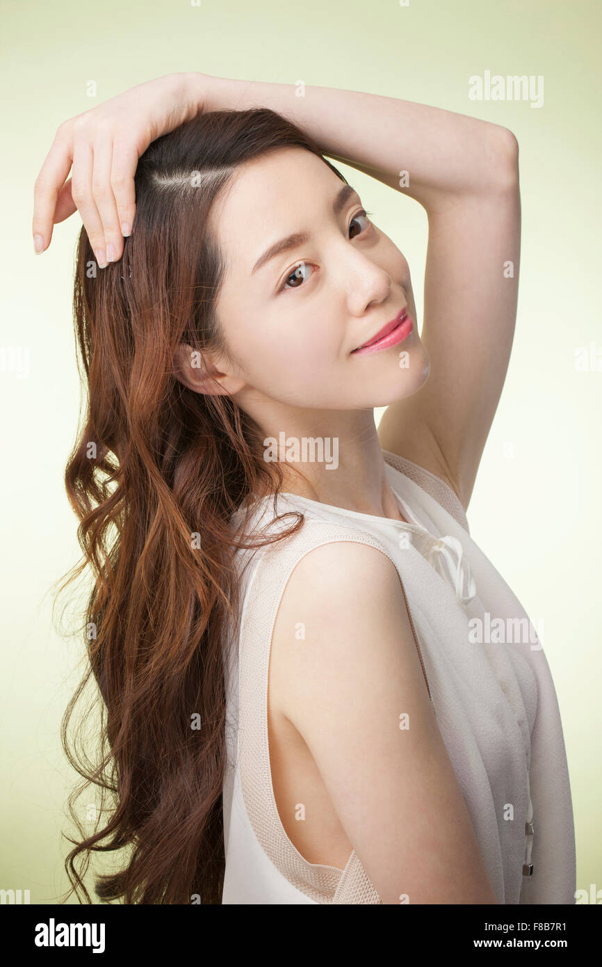 Korean Woman With Long Wavy Hair In White Sleeveless Shirt Putting