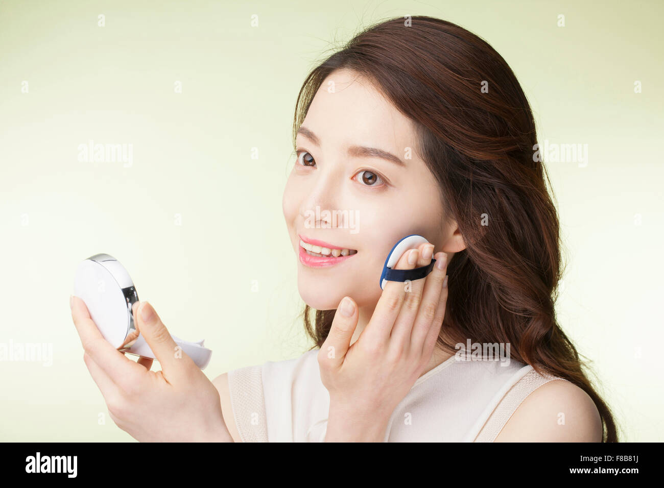 Korean Woman With Long Wavy Hair In White Shirt Putting On Make Up