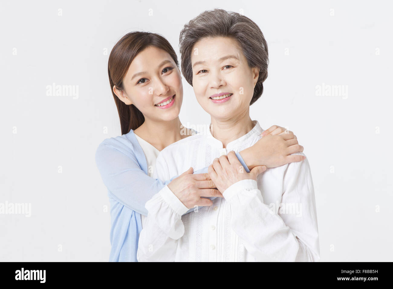 Mother and grown up daughter holding each other and smiling Stock Photo
