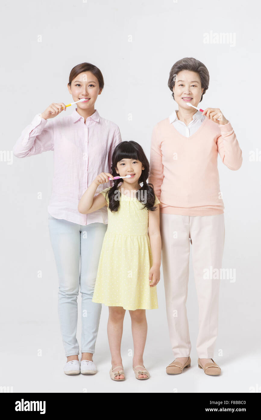 Mother, daughter, granddaughter standing together and brushing their