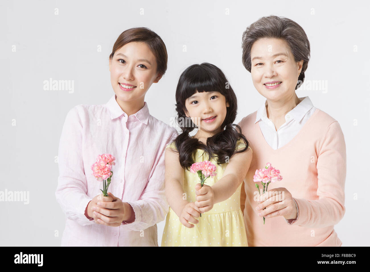 Mother, daughter, granddaughter holding flowers and smiling Stock Photo