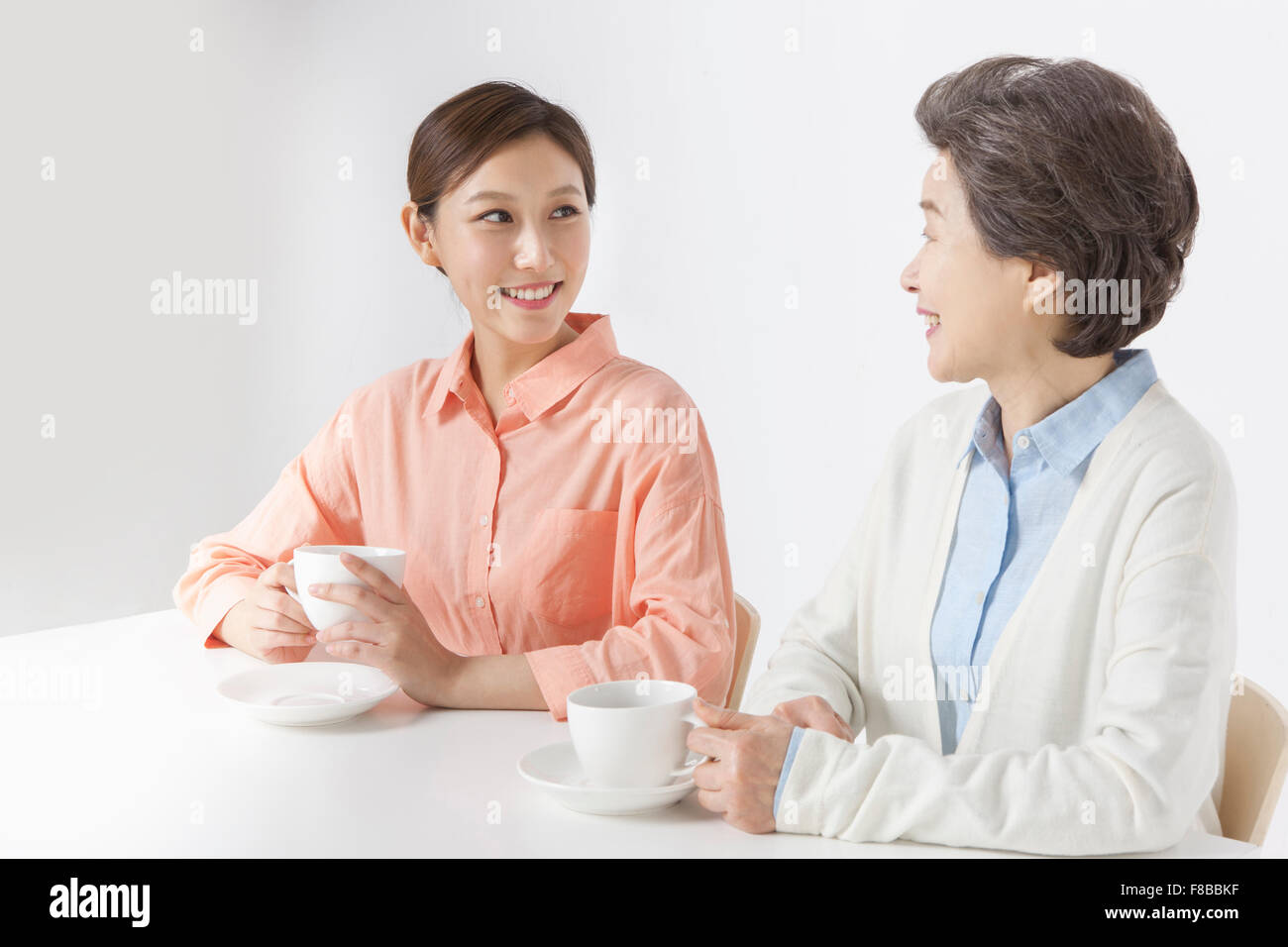 Mother and daughter sitting at table and having tea time Stock Photo