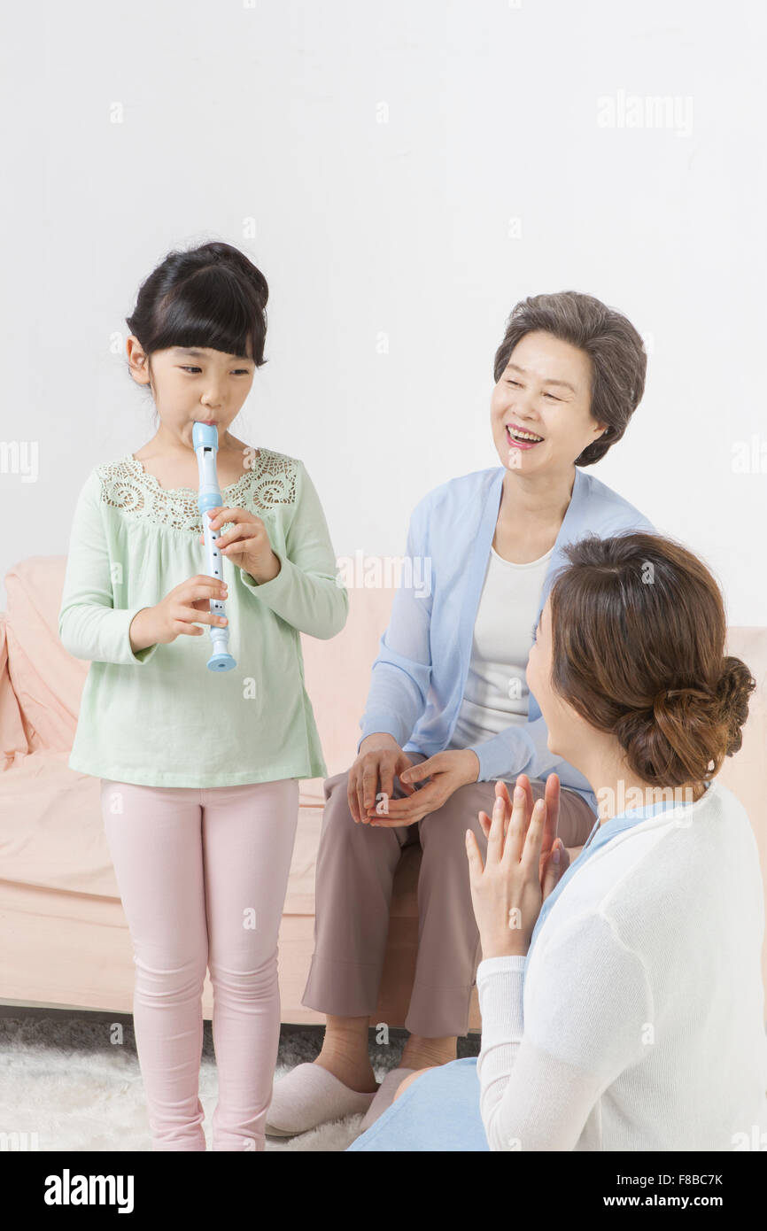 Granddaughter playing an instrument and grandmother and mother being happy looking at her Stock Photo