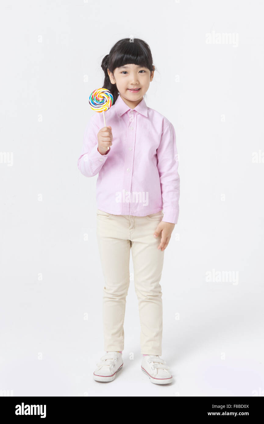 Girl with pony tail hair style in pink shirt standing and holding a lollipop Stock Photo