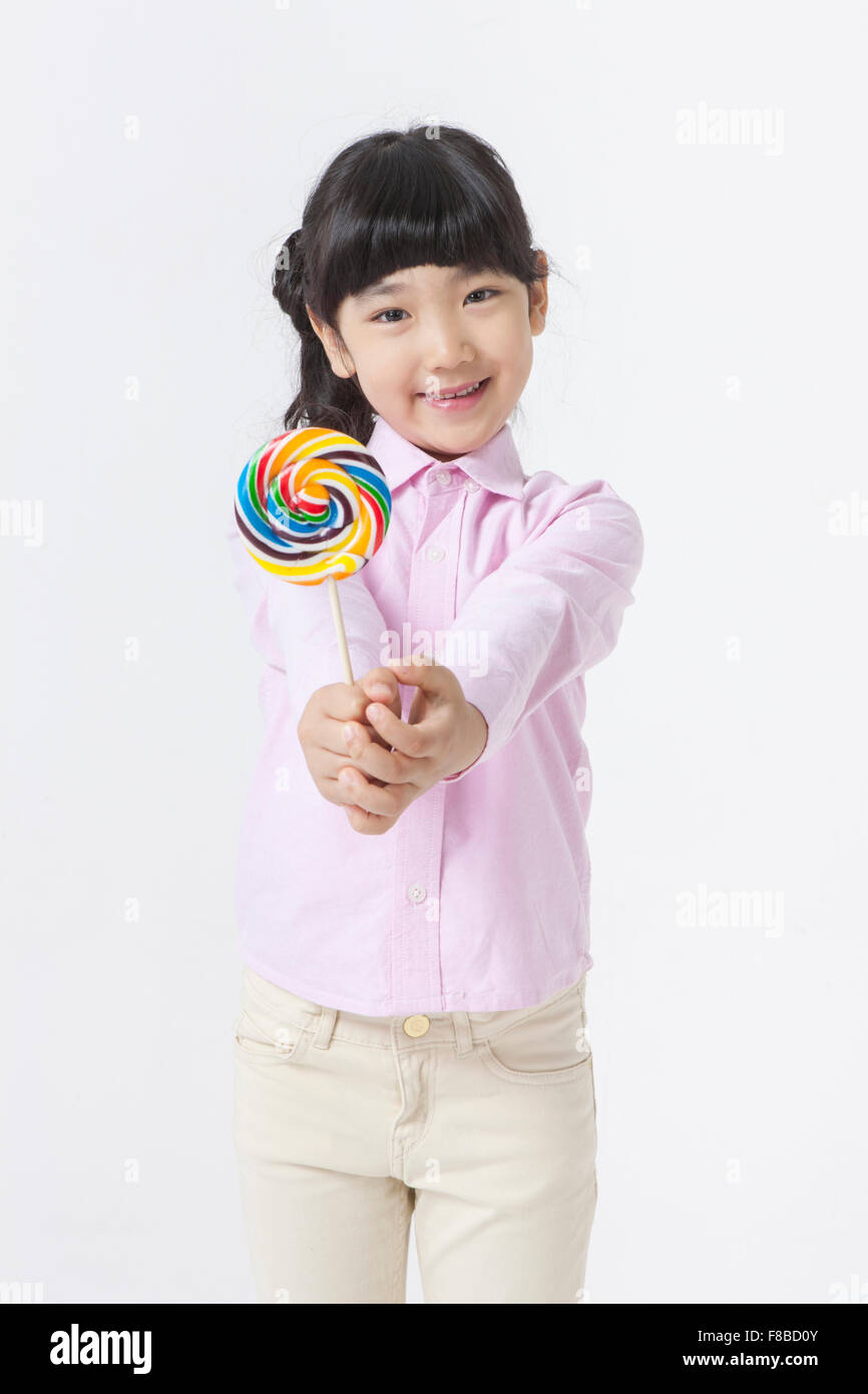 Girl with pony tail hair style in pink shirt holding a lollipop forward Stock Photo
