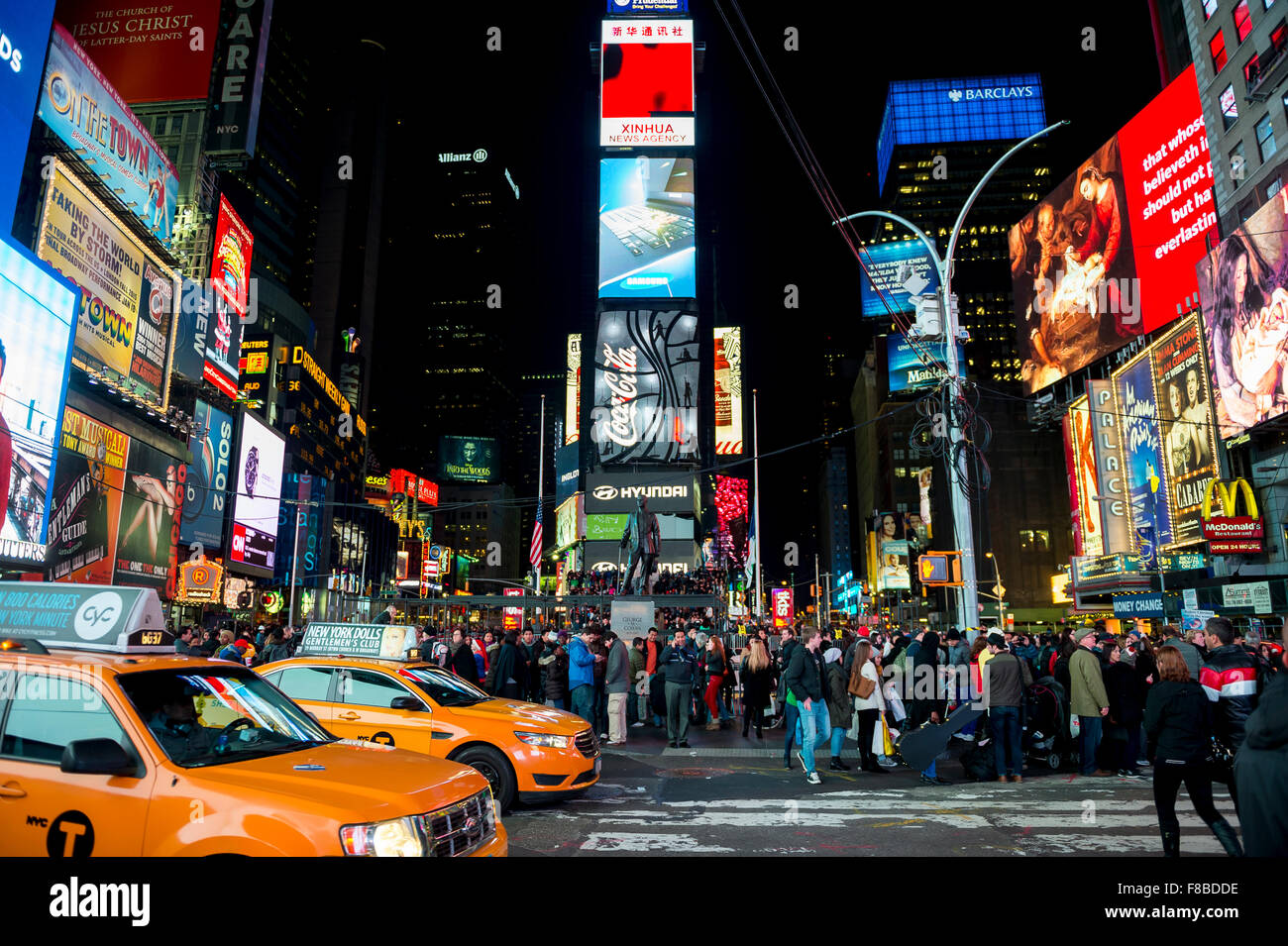 NEW YORK CITY, USA - DECEMBER 27, 2014: Yellow New York taxis pass crowds gathering under the bright lights of Times Square. Stock Photo