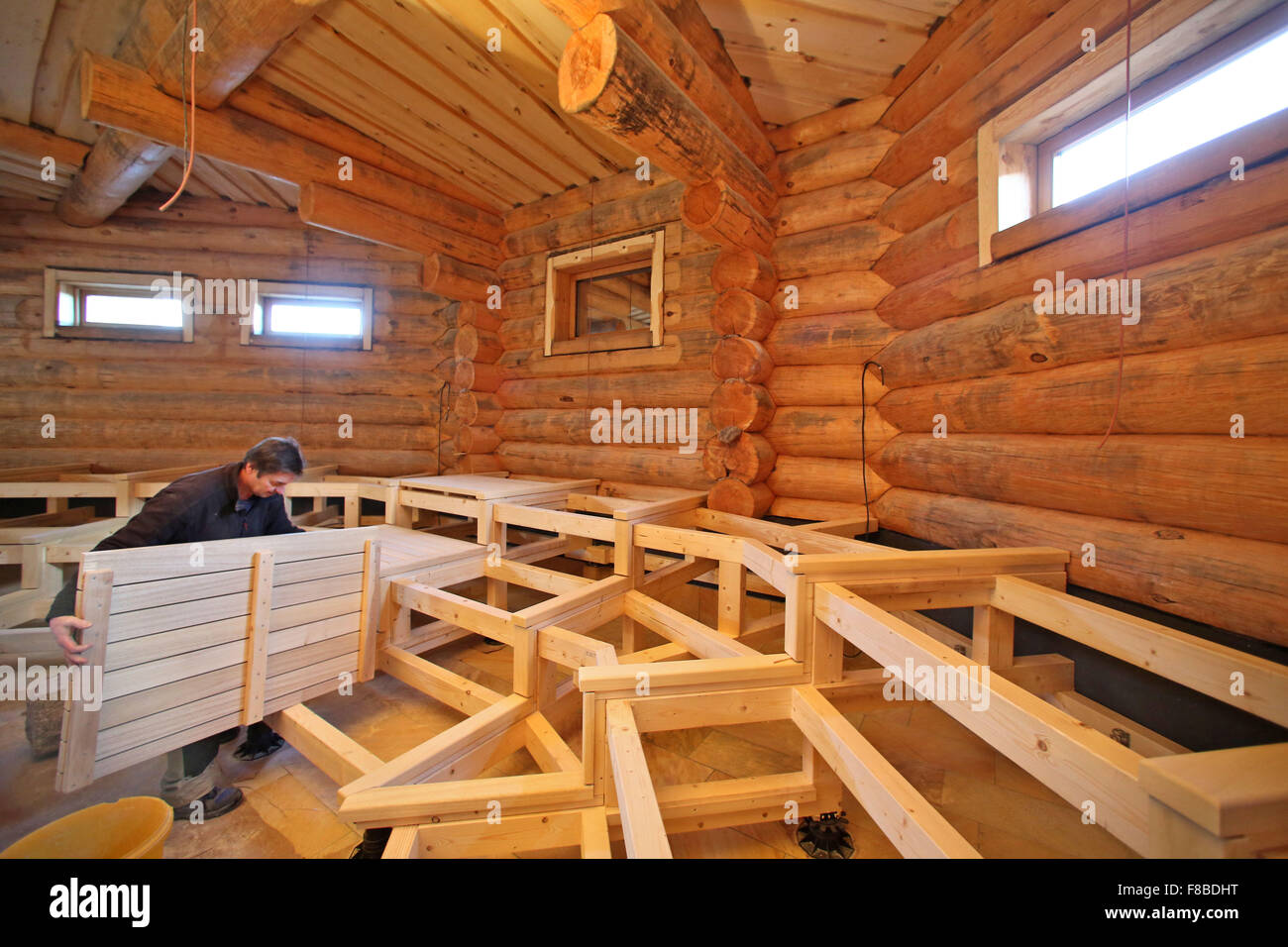 Carpenter Robby Weiss working on benches for a large new Russian sauna at the Badegaerten (lit. bathing gardens) in Eibenstock, Germany, 3 December 2015. On New Year's Eve, between 80 and 120 guests are due to attend the first sauna here. A total of 500 beams of Siberian larch were used in the construction of the 20-metre-high event sauna. The sauna along with its outdoor area are due to be completed in April 2016, at a cost of one million euros. PHOTO: JAN WOITAS Stock Photo