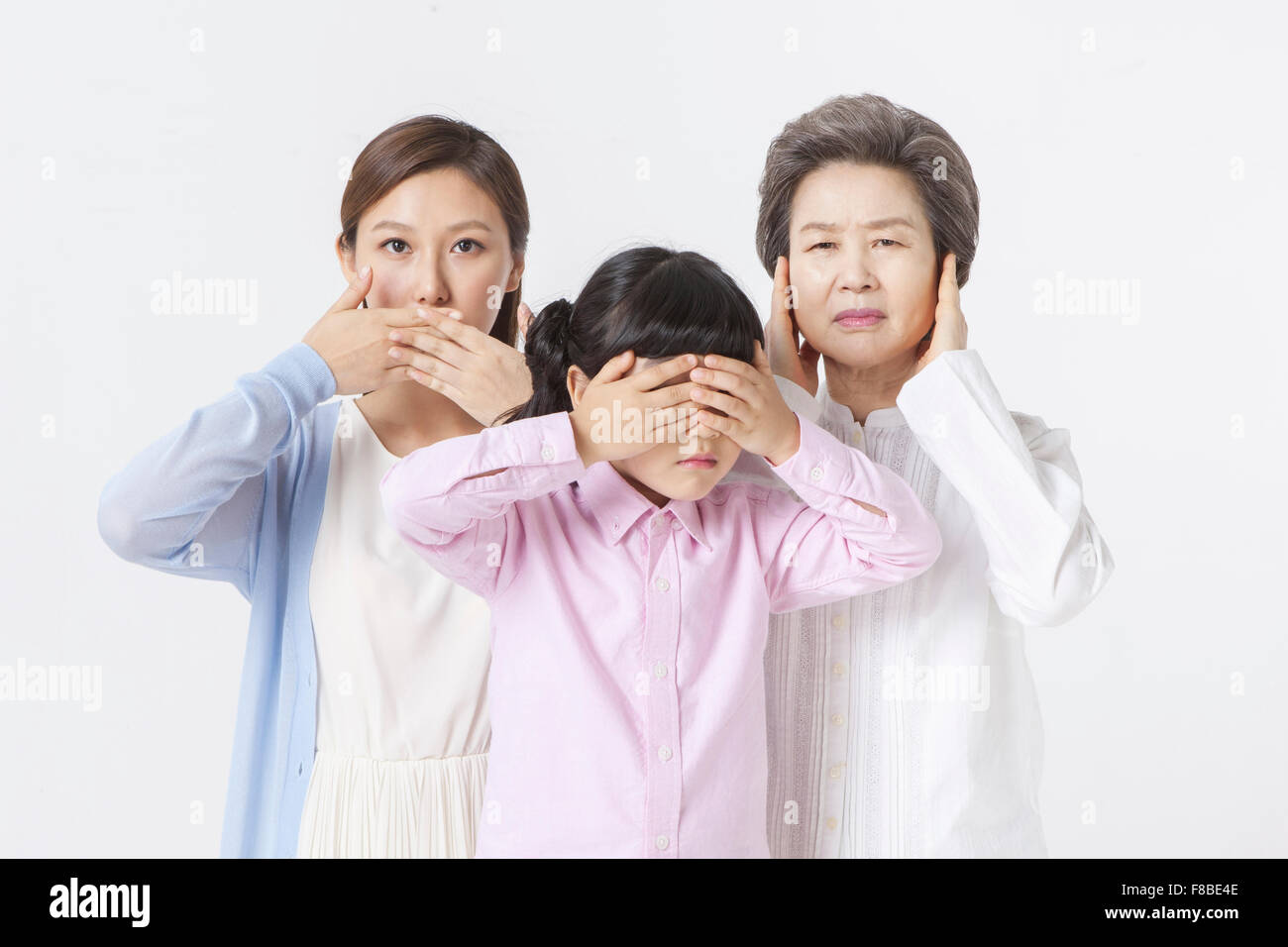 Grandmother blocking her ears, mother covering her mouth, and granddaughter covering her eyes Stock Photo