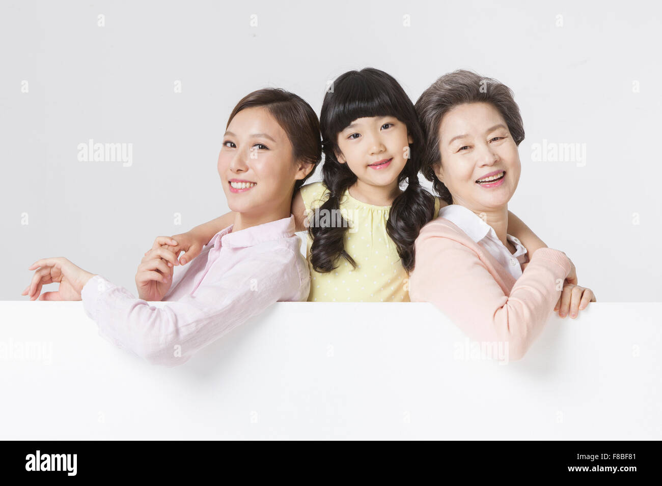 Mother, daughter, and grandmother together with white copy space under them Stock Photo